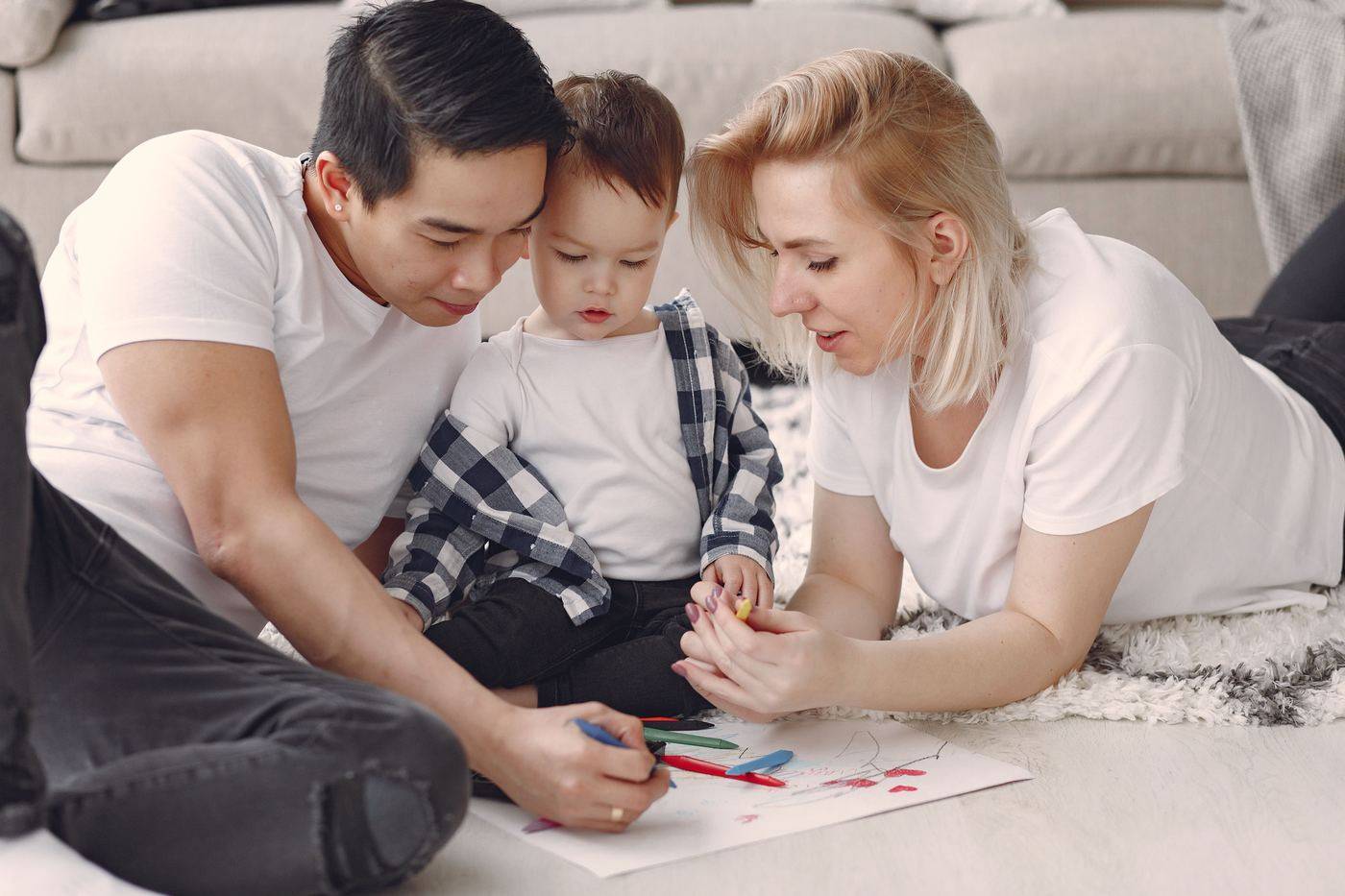 Two parents drawing on the floor with their toddler